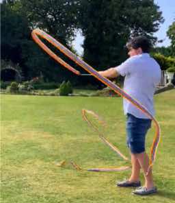 Person frolicking with a ribbon on the grass outside the Autscape venue.